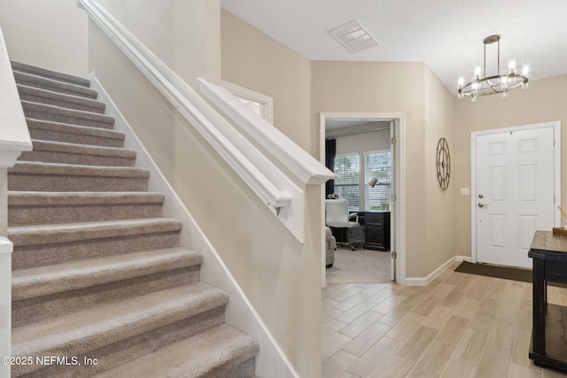 75743 Spoonbill Ln, Yulee, FL 32097 - entrance foyer with light wood-style flooring, visible vents, stairs, baseboards, and a notable chandelier