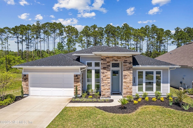 prairie-style home featuring roof with shingles, stone siding, a front lawn, a garage, and concrete driveway