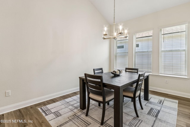 dining area featuring baseboards, wood finished floors, a notable chandelier, and vaulted ceiling