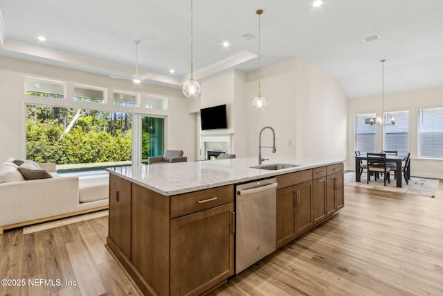 kitchen featuring open floor plan, dishwasher, a sink, and a tray ceiling