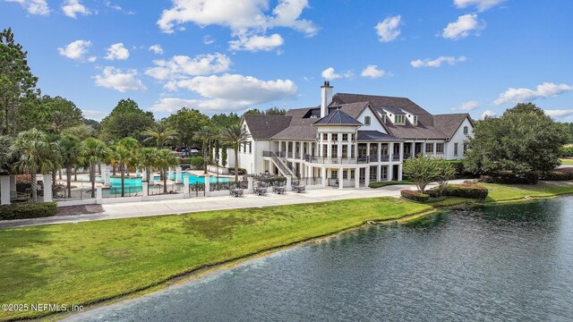 rear view of property with a patio, a yard, and a water view