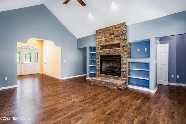 unfurnished living room featuring high vaulted ceiling, a ceiling fan, a stone fireplace, wood finished floors, and baseboards