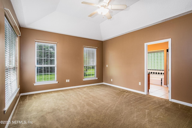 unfurnished bedroom with ensuite bathroom, baseboards, a ceiling fan, carpet, and vaulted ceiling