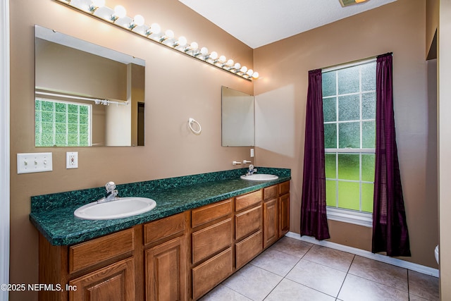 bathroom with tile patterned flooring, double vanity, baseboards, and a sink