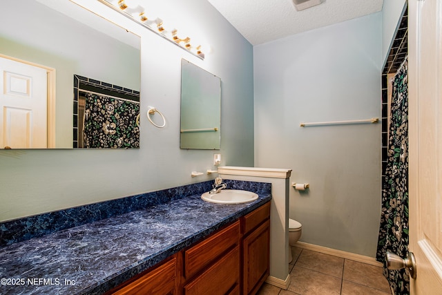 bathroom with vanity, baseboards, tile patterned flooring, a textured ceiling, and toilet