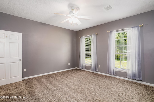 carpeted spare room with visible vents, ceiling fan, baseboards, and a textured ceiling