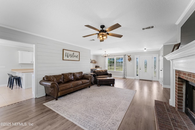 12531 County Road 121, Bryceville, FL 32009 - living area with a fireplace, a textured ceiling, visible vents, ceiling fan with notable chandelier, and wood finished floors
