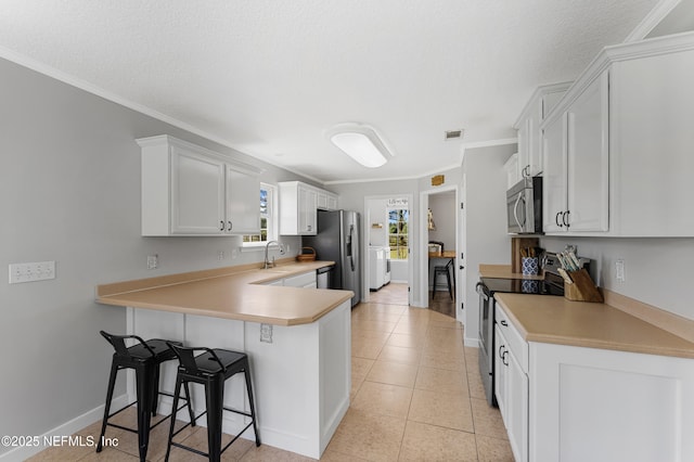 12531 County Road 121, Bryceville, FL 32009 - kitchen featuring a kitchen breakfast bar, a peninsula, light countertops, crown molding, and appliances with stainless steel finishes