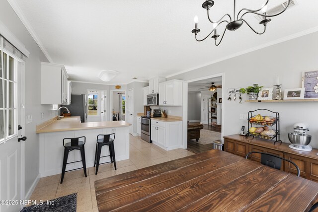 12531 County Road 121, Bryceville, FL 32009 - kitchen with light tile patterned floors, a peninsula, white cabinetry, a breakfast bar area, and stainless steel appliances