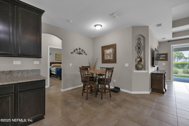 dining room featuring arched walkways, baseboards, light tile patterned flooring, and visible vents