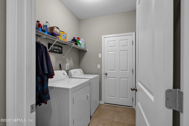 clothes washing area featuring washing machine and clothes dryer, a textured ceiling, laundry area, and light tile patterned floors