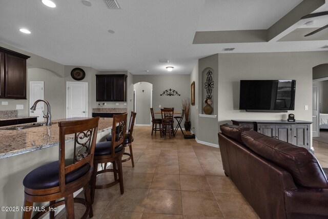 living area with visible vents, arched walkways, light tile patterned floors, baseboards, and recessed lighting