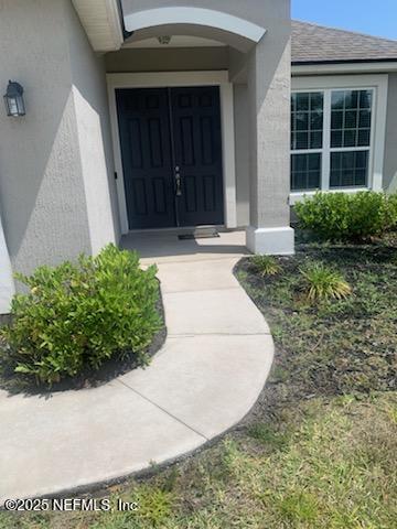 property entrance with a shingled roof and stucco siding