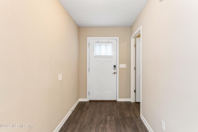 doorway with a textured ceiling, dark wood-style floors, and baseboards