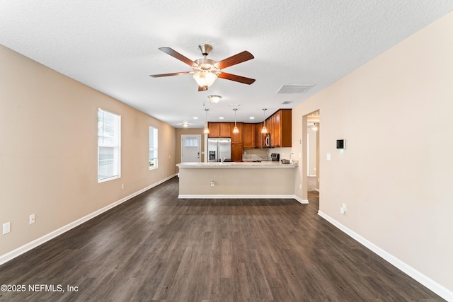 unfurnished living room with dark wood-style floors, ceiling fan, visible vents, baseboards, and a textured ceiling
