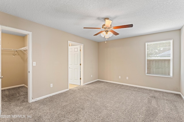 unfurnished bedroom featuring carpet, a closet, baseboards, and a walk in closet