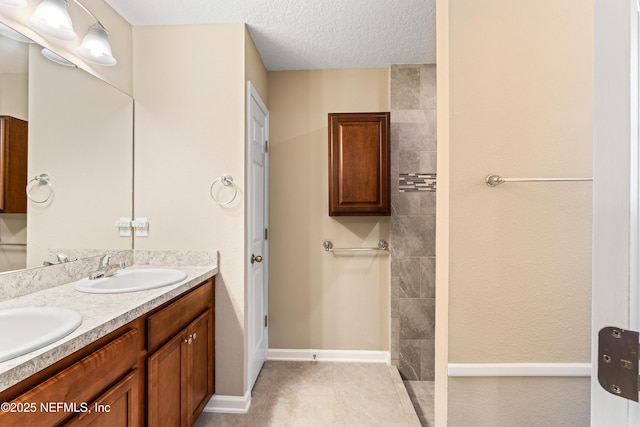 full bath featuring walk in shower, a textured ceiling, double vanity, and a sink