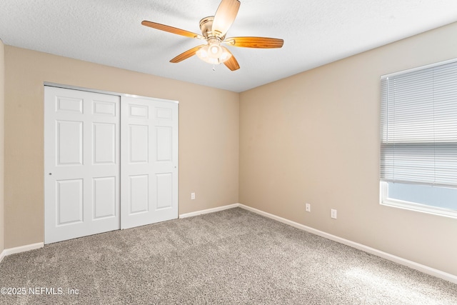 unfurnished bedroom featuring carpet floors, a closet, ceiling fan, baseboards, and a textured ceiling
