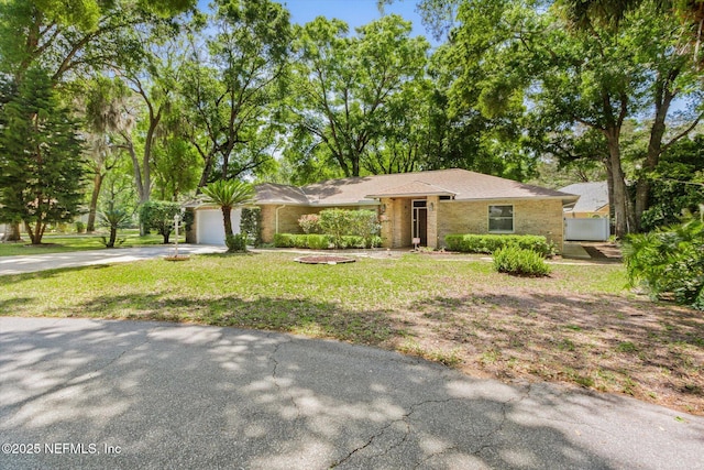 view of front facade featuring a front yard, brick siding, driveway, and an attached garage