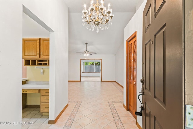 entrance foyer with a notable chandelier, baseboards, vaulted ceiling, built in study area, and light tile patterned floors