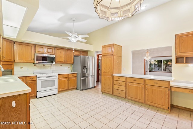 kitchen with a sink, light countertops, ceiling fan with notable chandelier, high vaulted ceiling, and stainless steel appliances