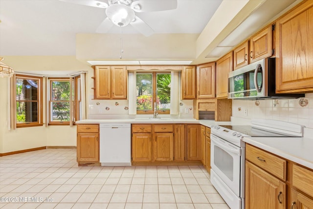 kitchen with white appliances, light countertops, a sink, decorative backsplash, and plenty of natural light