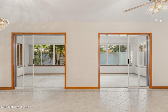 empty room with tile patterned floors, baseboards, and a ceiling fan