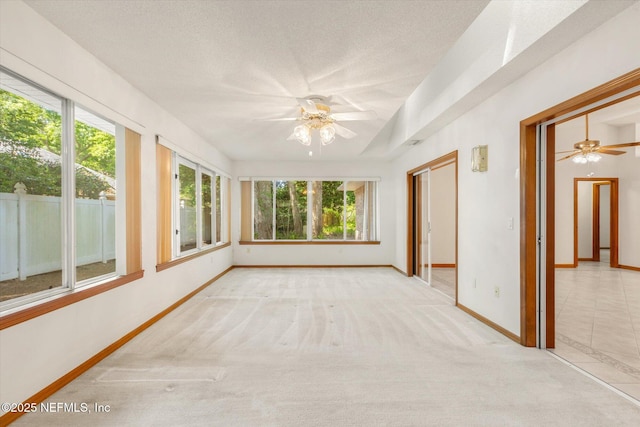 unfurnished sunroom with a textured ceiling, carpet flooring, and baseboards