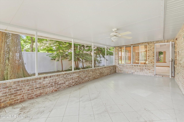 unfurnished sunroom featuring ceiling fan and plenty of natural light