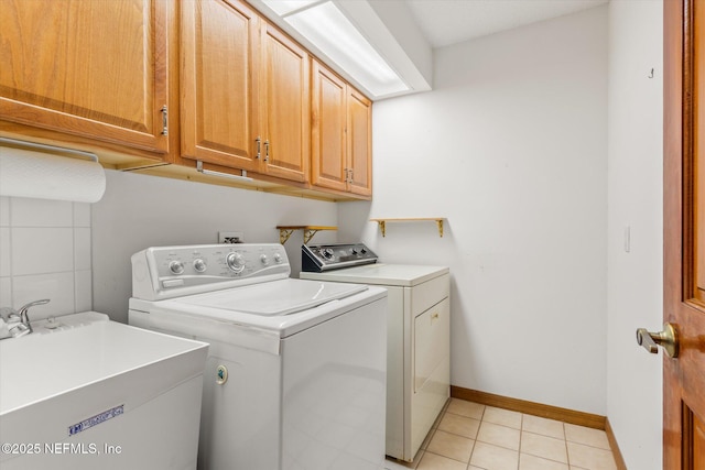clothes washing area featuring light tile patterned flooring, a sink, baseboards, cabinet space, and washer and clothes dryer