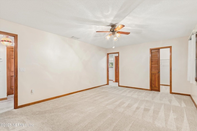unfurnished room featuring baseboards, a textured ceiling, a ceiling fan, visible vents, and light colored carpet