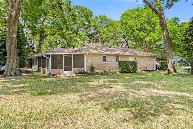 back of property with a yard, brick siding, and a sunroom