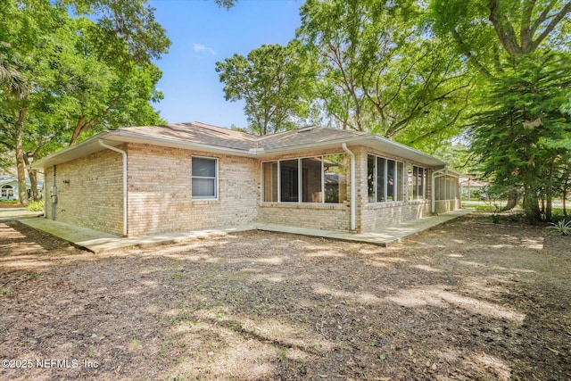 rear view of property with brick siding and a sunroom