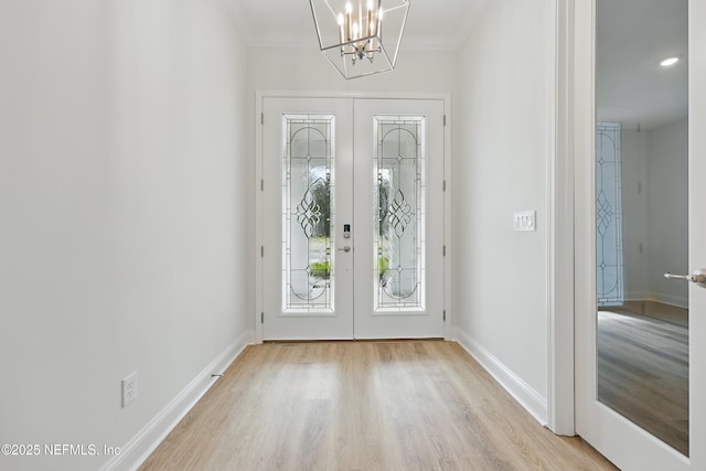 entrance foyer with a notable chandelier, french doors, light wood-type flooring, and baseboards
