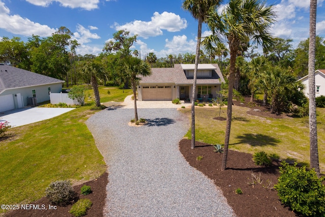 355 Lambert Ave, Flagler Beach, FL 32136 - view of front of house featuring a front yard, gravel driveway, an attached garage, cooling unit, and roof with shingles