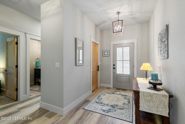 355 Lambert Ave, Flagler Beach, FL 32136 - entrance foyer with light wood-type flooring, baseboards, and a notable chandelier