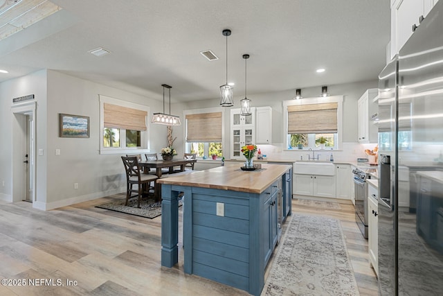 355 Lambert Ave, Flagler Beach, FL 32136 - kitchen with light wood-style flooring, tasteful backsplash, white cabinets, stainless steel appliances, and wooden counters