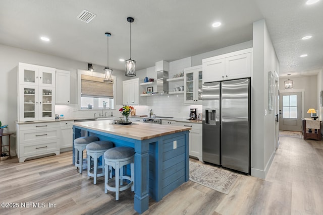 355 Lambert Ave, Flagler Beach, FL 32136 - kitchen with a kitchen breakfast bar, butcher block counters, stainless steel refrigerator with ice dispenser, visible vents, and a sink