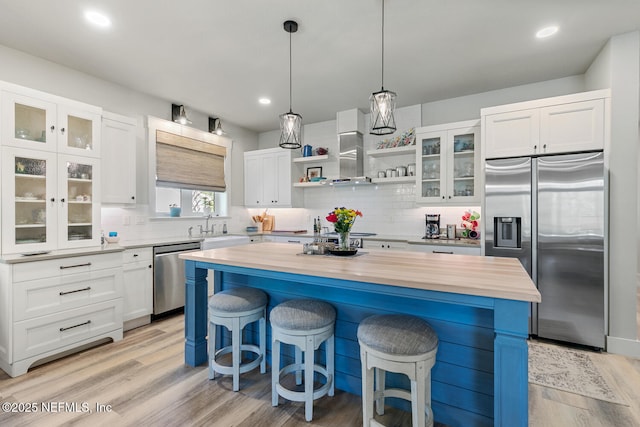 355 Lambert Ave, Flagler Beach, FL 32136 - kitchen featuring wall chimney exhaust hood, butcher block counters, a kitchen island, stainless steel appliances, and a breakfast bar area