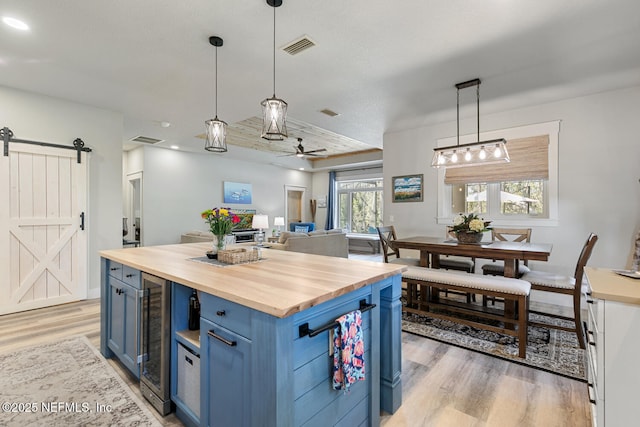 355 Lambert Ave, Flagler Beach, FL 32136 - kitchen featuring a barn door, ceiling fan, wooden counters, light wood-style flooring, and blue cabinetry