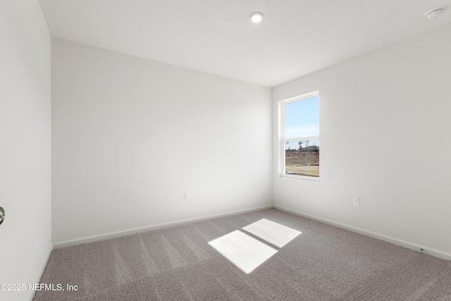 carpeted empty room featuring baseboards