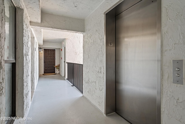 275 1st St S Unit 504, Jacksonville Beach, FL 32250 - hallway with elevator, a textured wall, and concrete floors