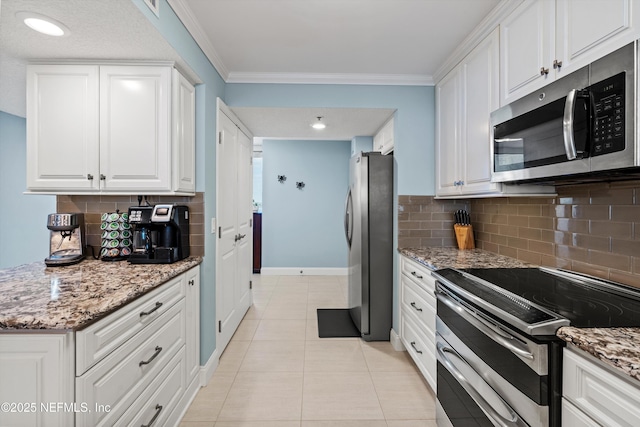 275 1st St S Unit 504, Jacksonville Beach, FL 32250 - kitchen with appliances with stainless steel finishes, baseboards, white cabinetry, backsplash, and ornamental molding