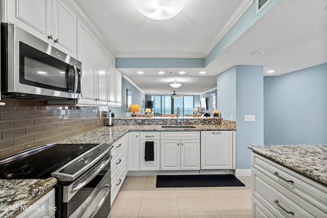 275 1st St S Unit 504, Jacksonville Beach, FL 32250 - kitchen featuring appliances with stainless steel finishes, a sink, decorative backsplash, white cabinets, and crown molding
