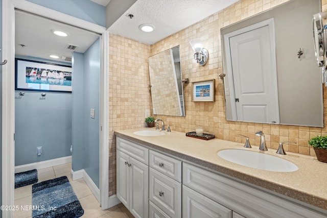 275 1st St S Unit 504, Jacksonville Beach, FL 32250 - bathroom featuring tile patterned flooring, double vanity, tasteful backsplash, a textured ceiling, and baseboards