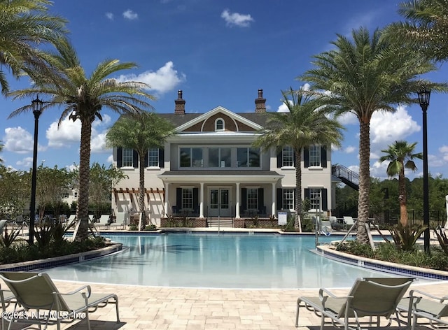 114 Fremont Ave, Saint Augustine, FL 32095 - back of property with french doors, stucco siding, a community pool, and a chimney