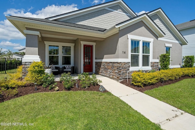 114 Fremont Ave, Saint Augustine, FL 32095 - view of front of home with a front yard, a porch, stucco siding, and stone siding