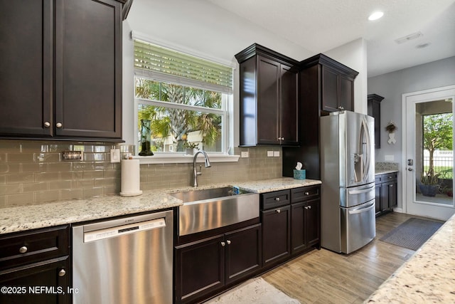 114 Fremont Ave, Saint Augustine, FL 32095 - kitchen featuring tasteful backsplash, light wood-type flooring, light stone countertops, stainless steel appliances, and a sink