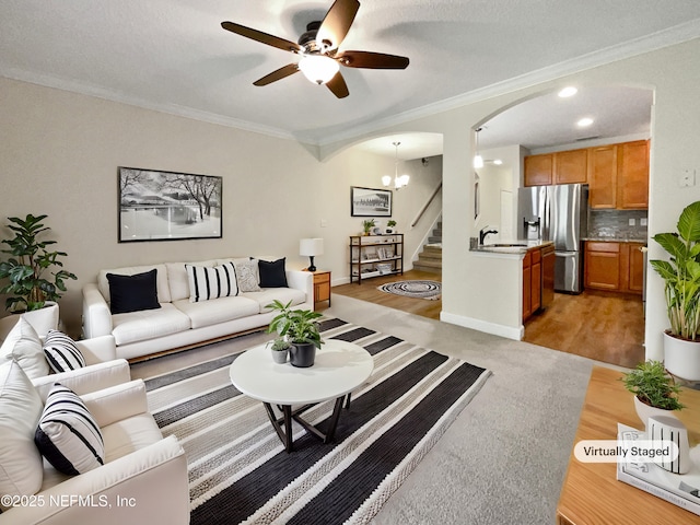 1825 Lago Del Sur Dr, Middleburg, FL 32068 - living room with arched walkways, ornamental molding, a ceiling fan, light wood-style floors, and stairs