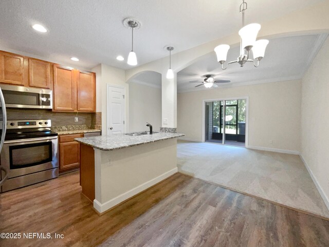 1825 Lago Del Sur Dr, Middleburg, FL 32068 - kitchen featuring backsplash, light stone countertops, appliances with stainless steel finishes, ceiling fan with notable chandelier, and a sink